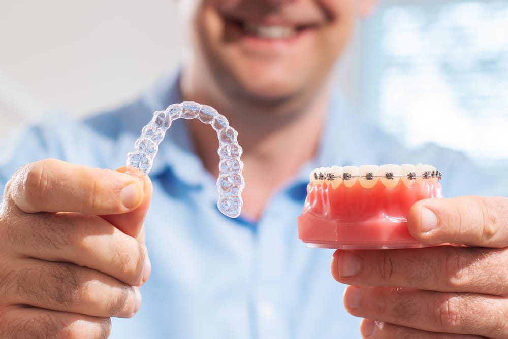 Dentist holding invisalign and traditional braces Dentist holding invisalign and traditional braces