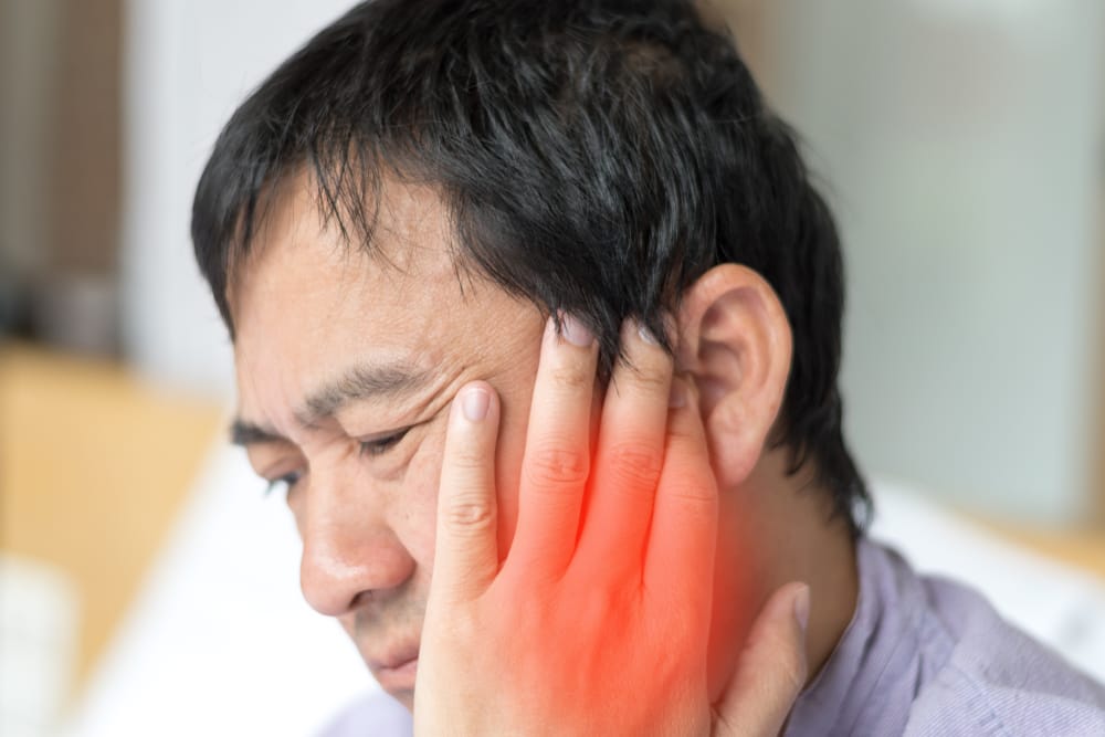 Man Experiencing Intense Jaw Pain – emergency dentist San Diego Middle-aged man pressing on his cheek and jaw in visible pain, with red highlight indicating inflammation or dental emergency – emergency dentist San Diego