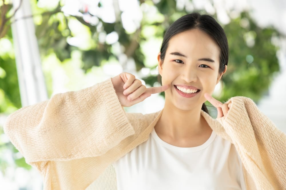 smiling while showing her healthy teeth - oral surgery