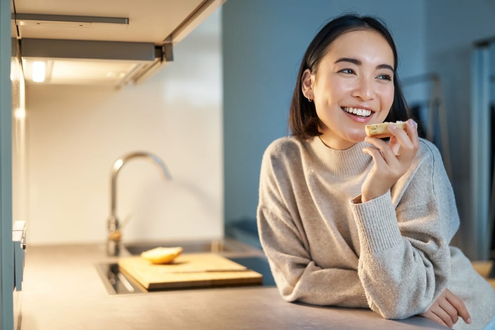 woman eating by the kitchen sink - Dental Sealants