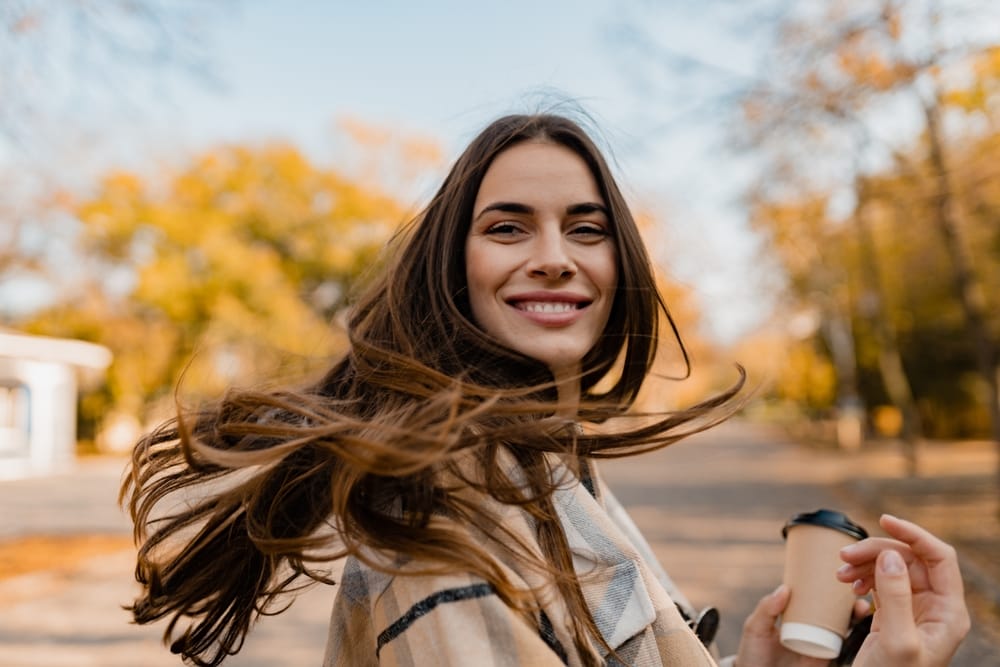 young smiling woman walking in autumn park - veneers